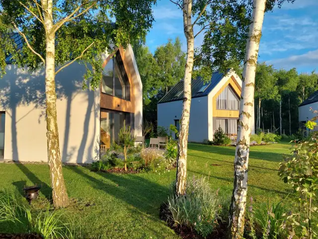 Nowe domki nad morzem z psem czekają na gości. Słoneczny dzień, zieleń i spokój.