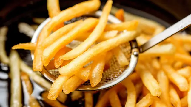 Chrupiące, złociste frytki na sicie do odcedzania.