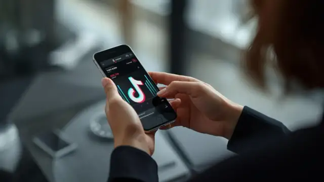 Dłonie trzymające smartfon z otwartą aplikacją TikTok i widocznymi statystykami.