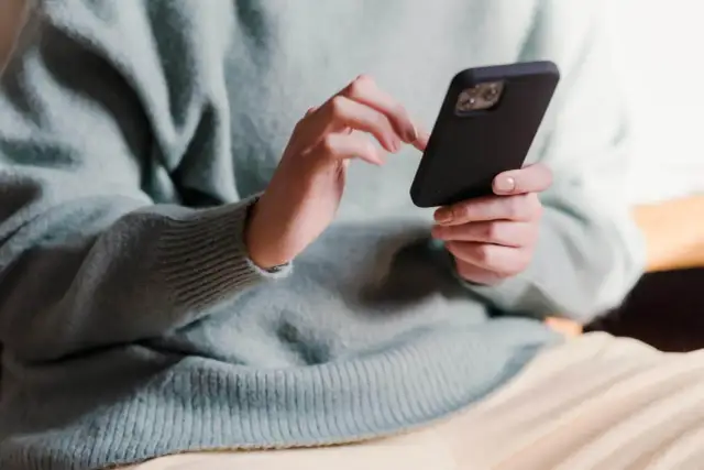 Dłonie trzymające telefon, zastanawiające się, co napisać po kłótni.