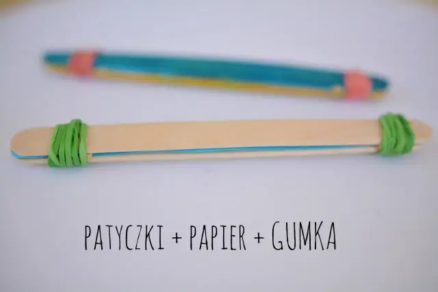 Proste instrumenty muzyczne do zrobienia: patyczki, papier i gumka. Dwa patyczki połączone gumkami, jeden z kolorowym papierem w środku.