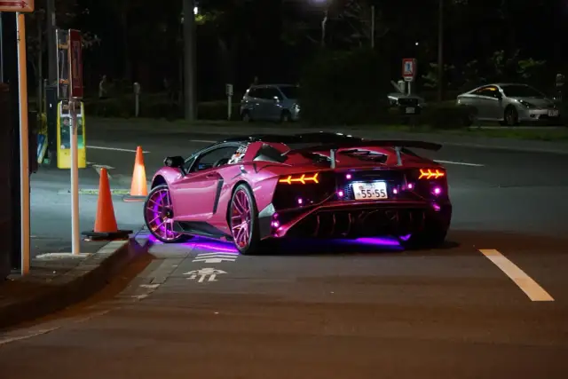 Różowy Lamborghini z neonowym podświetleniem na ulicy nocą.