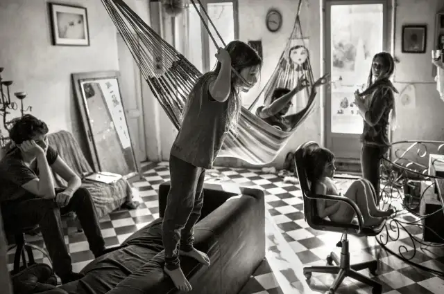 Dzieci bawią się w hamakach, jak na zdjęciach Alain Laboile. Jedno stoi na kanapie, inne w fotelu.