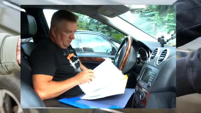 Mężczyzna w samochodzie przegląda dokumenty. Może to być związane z zastawem rejestrowym na samochodzie.