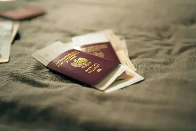 Kilka paszportów leży na szarym materiale. Zastanawiasz się, jak wyrobić paszport? To pierwszy krok do podróży!