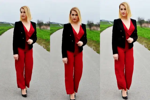 Kobieta w czerwonym kombinezonie i czarnej marynarce prezentuje stylowe czerwony kombinezon stylizacje na tle drogi i zieleni.