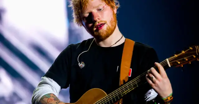 Ed Sheeran gra na gitarze akustycznej na scenie.