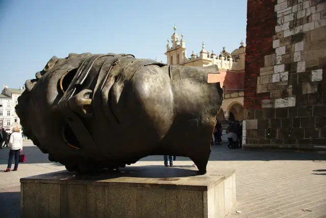 Ogromna, metalowa rzeźba głowy Igora Mitoraja na placu w Krakowie.