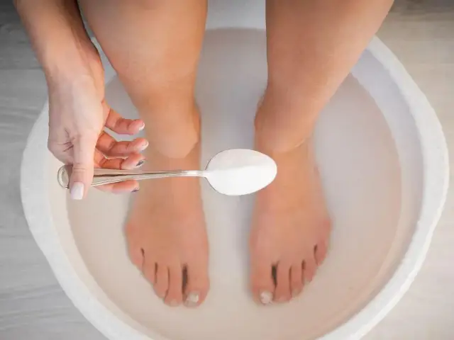 Kąpiel stóp w sodzie pomaga na opuchliznę i zmęczenie. Łyżeczka sody trafia do miski z wodą.