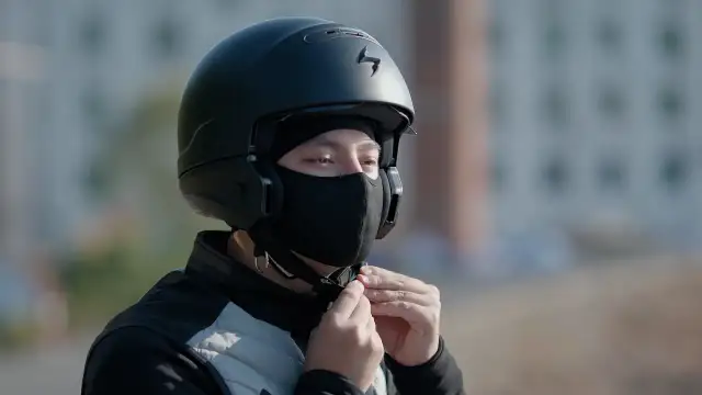 Motocyklista zapina czarną kominiarkę pod kaskiem.