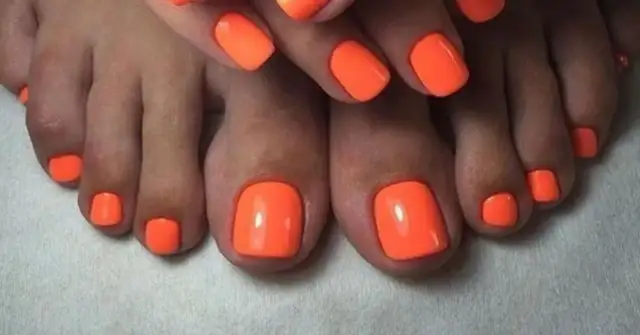 Paznokcie u nóg neonowe, w intensywnym pomarańczowym kolorze, przyciągają wzrok. Idealny manicure na lato.