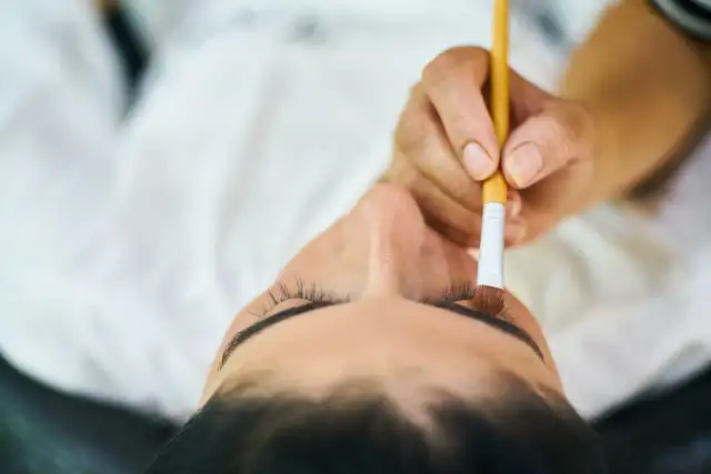 Stylistka rzęs aplikuje tusz. Zastanawiasz się, ile zarabia stylistka rzęs?