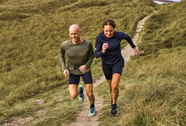 Para biegnie po ścieżce wśród traw.