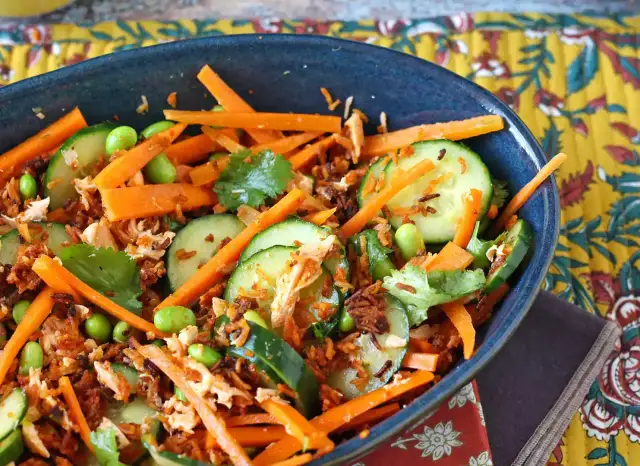 Sałatka z marchewką, ogórkiem, edamame i kolendrą w niebieskiej misce.