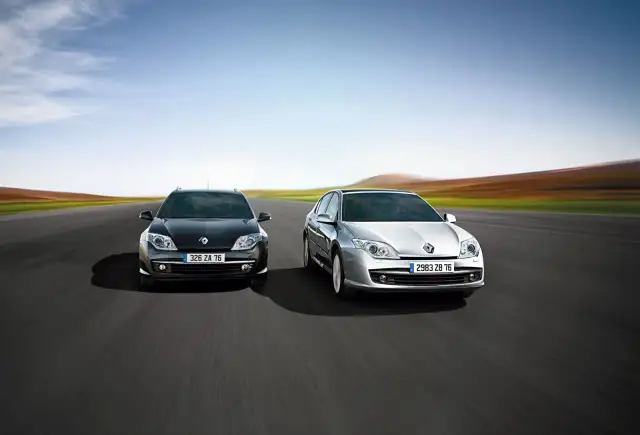 Dwa modele Renault Laguna 3, czarny i srebrny, pędzą po pustej drodze na tle rozmytego krajobrazu.