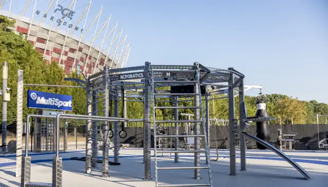 Zewnętrzna siłownia z konstrukcją do ćwiczeń, workiem treningowym i tablicą Multisport.