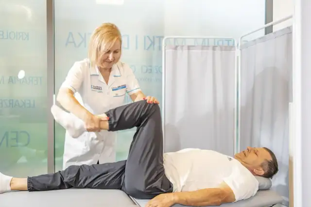 Fizjoterapeutka wykonuje ćwiczenia z pacjentem leżącym na kozetce.
