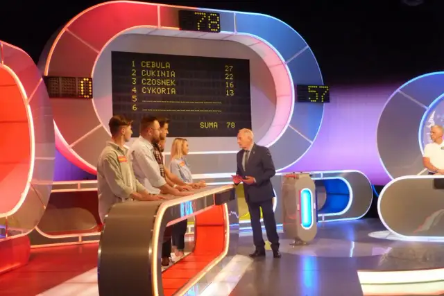 Uczestnicy Familiady stoją przy pulpicie, a na ekranie widnieje lista odpowiedzi i suma punktów.