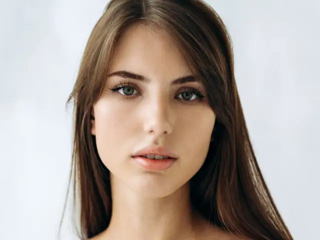 Delikatna twarz kobiety o zielonych oczach i brązowych włosach, uchwycona w subtelnym, **stylu soft**.