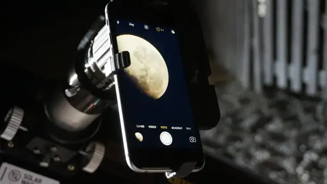 Telefon z aparatem przy teleskopie, gotowy do uchwycenia piękna Księżyca. Dowiedz się, jak fotografować księżyc.