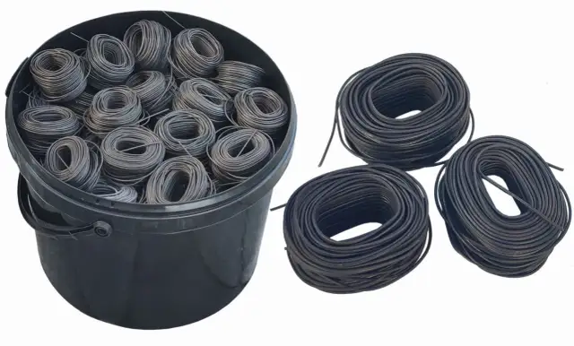 Duży czarny kubeł wypełniony motkami drutu wiązałkowego. Obok trzy luźne zwoje drutu.