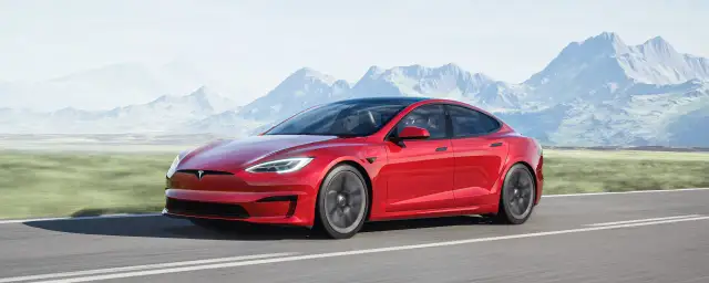 Czerwony Tesla Model S jedzie po drodze, a w tle widać góry. Tesla co to? To przyszłość motoryzacji.