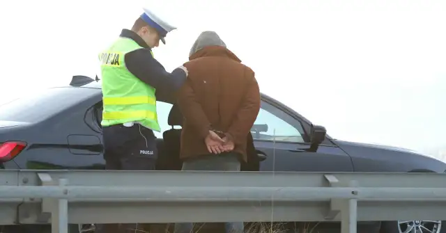 Policjant zakłada kajdanki zatrzymanemu mężczyźnie. Nowelizacja kodeksu karnego w praktyce.