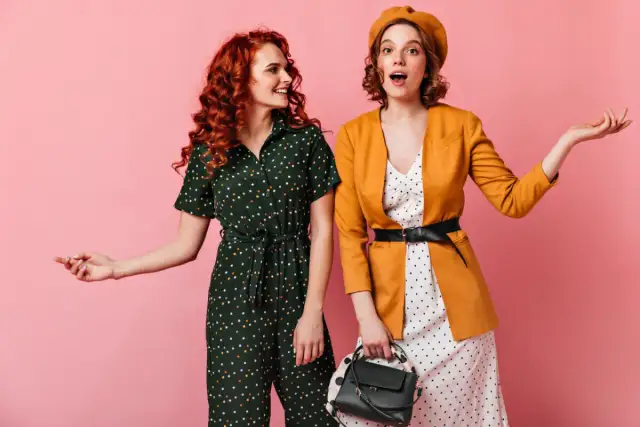 Dwie kobiety w strojach w groszki i stylu vintage na różowym tle.