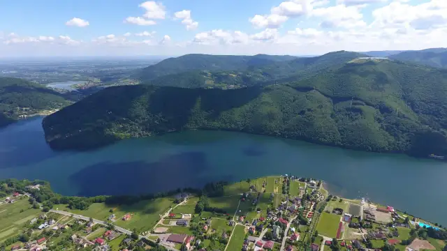 Malownicze widoki na jezioro i góry w Międzybrodziu Bialskim. W oddali widać zabudowania i pola.