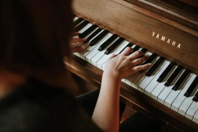 Dłonie na klawiaturze pianina Yamaha. Rozpoczyna się nauka gry na pianinie online, odkrywanie melodii.