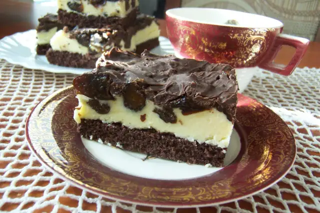 Pyszne ciasto pijana śliwka z kremem i polewą czekoladową na ozdobnym talerzyku.