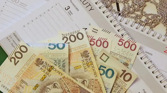 Polskie banknoty o nominałach 10, 50, 200 i 500 zł leżą na kalendarzu.