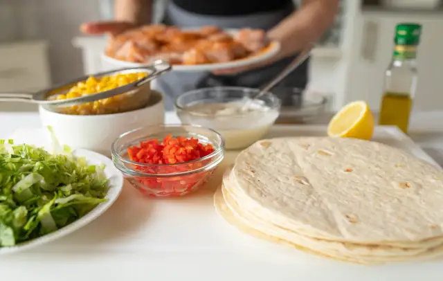 Składniki na zdrowe tortille: sałata, kukurydza, papryka, sos, cytryna i oliwa.