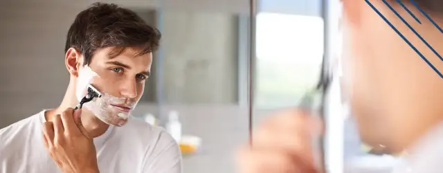 Mężczyzna goli twarz pianką do golenia maszynką.