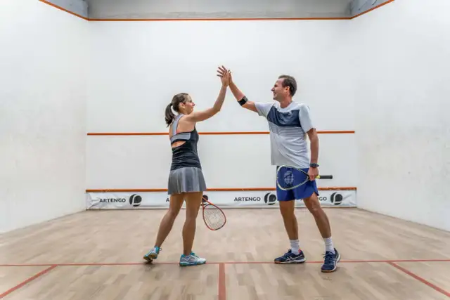Para grająca w squasha daje sobie piątkę na korcie.