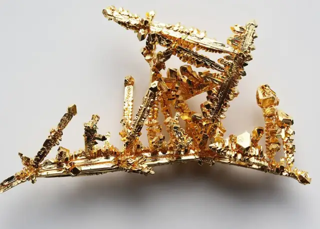 Złote kryształy o próbie 925, przypominające miniaturową architekturę, lśnią na jasnym tle. To próba 925 złoto czy srebro?