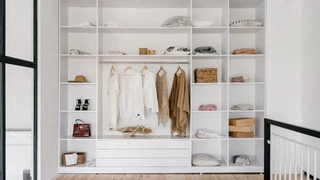 Otwarta szafa z drzwiami przesuwnymi, pełna ubrań i akcesoriów. Jak zrobić szafę z drzwiami przesuwnymi? Inspiracja.
