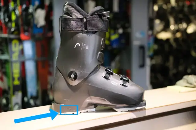 Szary but narciarski z niebieską strzałką wskazującą na rozmiar.