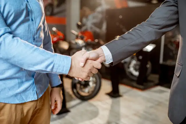 Uścisk dłoni na znak udanej umowy sprzedaży motocykla w salonie.