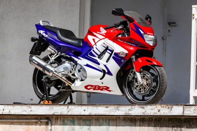 Czerwono-biało-niebieski motocykl sportowy Honda CBR 600 na stojaku.