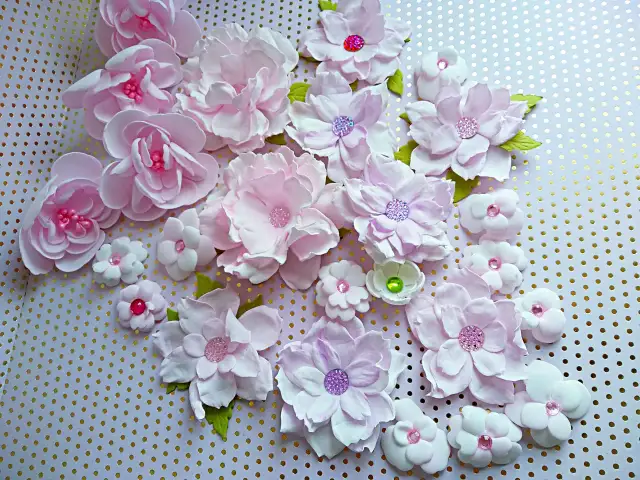 Kwiaty z pianki dekoracyjnej jak zrobić: delikatne, różowe kwiaty z pianki z błyszczącymi środkami, ułożone na tle w złote kropki.