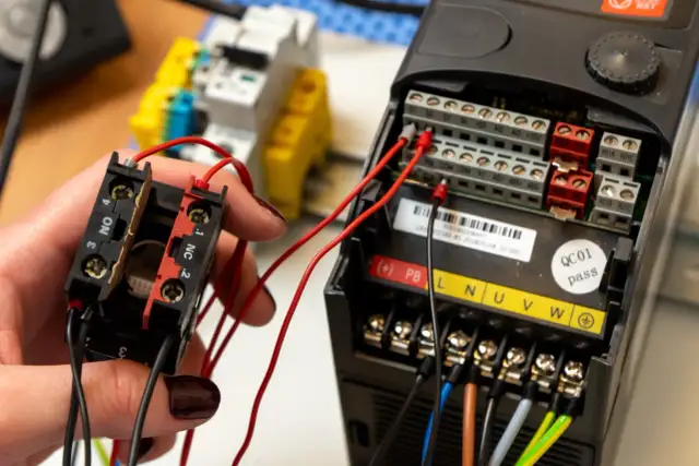 Ręczne podłączanie falownika do silnika. Widoczne przewody i zaciski sterujące.