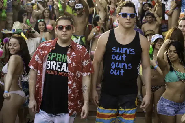 Schmidt i Jenko na imprezie w stylu "23 Jump Street". Schmidt w koszulce "Spring Break" i hawajskiej koszuli, Jenko w podkoszulku "Sun's out, guns out".