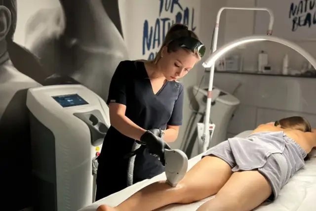 Profesjonalistka wykonuje zabieg depilacji laserowej nogi. To najlepszy laser do depilacji, zapewniający gładkość skóry.