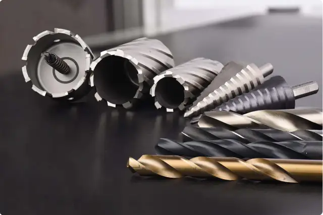 Różne rodzaje wierteł i otwornic ułożone na ciemnym tle.