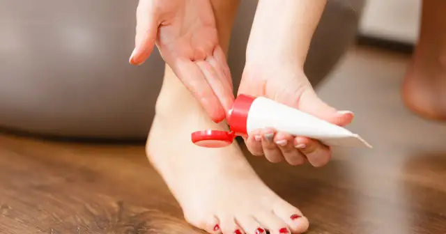 Kobieta aplikuje krem na stopę, być może szukając informacji o wyciąg z kasztanowca skutki uboczne.
