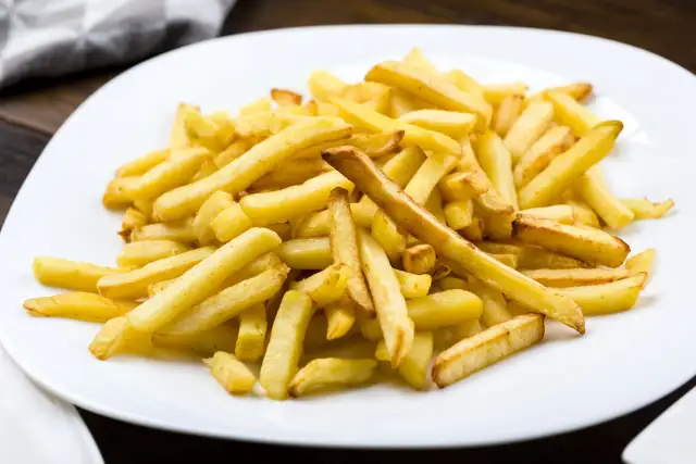Stos frytek na białym talerzu.