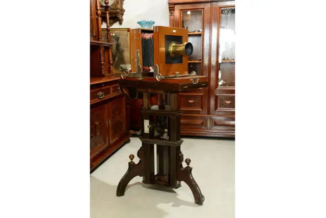 Antyczny aparat fotograficzny na drewnianym statywie z miechem i obiektywem.