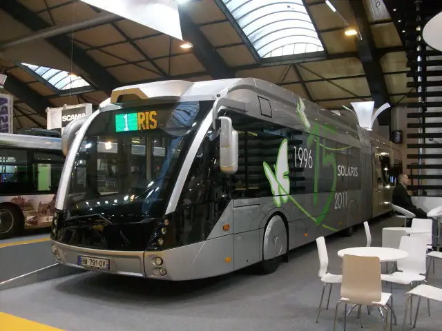 Nowoczesny, srebrny autobus Solaris z zielonymi zdobieniami i napisem "1 RIS".