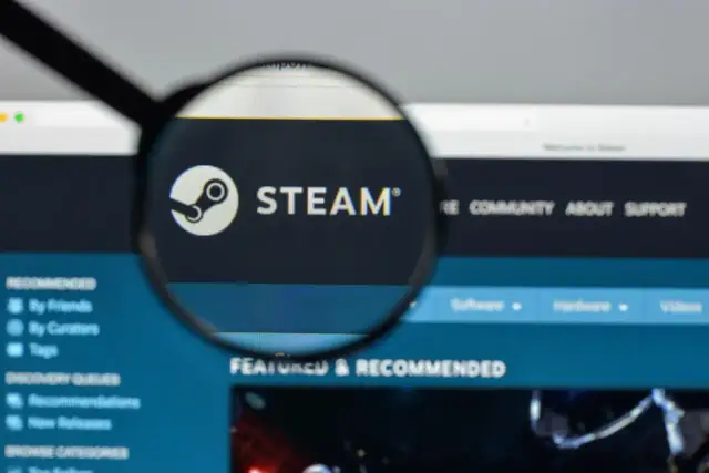 Lupa powiększa logo Steam na ekranie komputera.